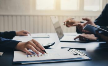 Person reviewing financial documents with a financial adviser, showcasing investment strategies, tax planning, and wealth management services in the UK.
