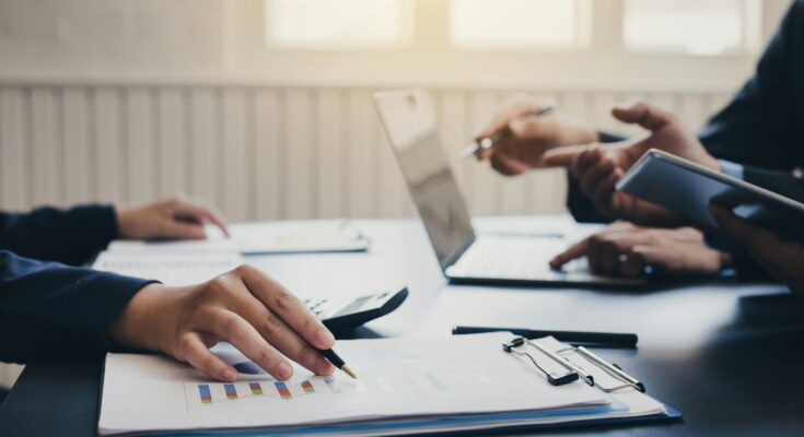 Person reviewing financial documents with a financial adviser, showcasing investment strategies, tax planning, and wealth management services in the UK.