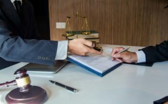 Client consulting with a legal professional, reviewing and signing important documents in an office setting, symbolized by a gavel and scales of justice in the background