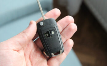 A broken car key fob with visible damage to the buttons and casing, lying on a white background
