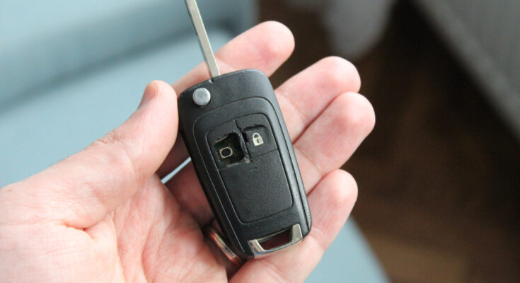 A broken car key fob with visible damage to the buttons and casing, lying on a white background