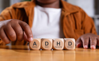 Wooden blocks stacked with the letters "ADHD" printed on them, symbolizing attention deficit hyperactivity disorder and its foundational impact.