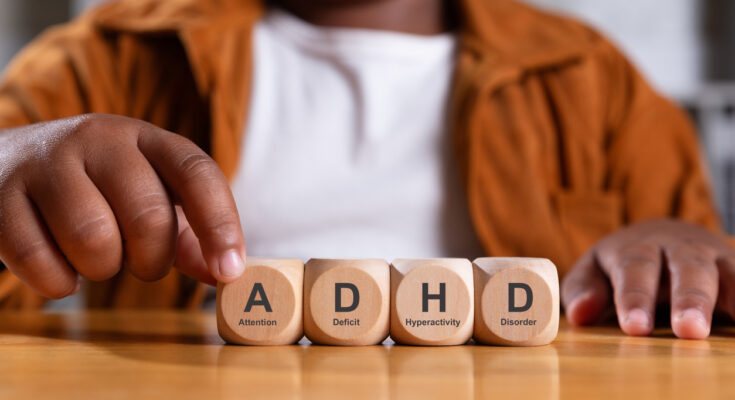 Wooden blocks stacked with the letters "ADHD" printed on them, symbolizing attention deficit hyperactivity disorder and its foundational impact.