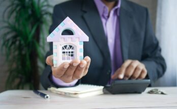 A mortgage broker holding a small house model, symbolizing guidance and support in finding the best mortgage or remortgage deals.