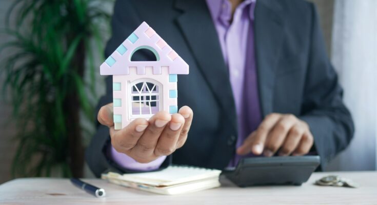 A mortgage broker holding a small house model, symbolizing guidance and support in finding the best mortgage or remortgage deals.
