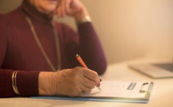 Elderly woman writing on a clipboard while reviewing costs to contest a will in the UK